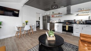 A modern kitchen with white cabinets, stainless steel appliances, and wooden shelves. - MODERN/Mins to Beach/walk to dwtn/Free parking (Tarpon Springs)