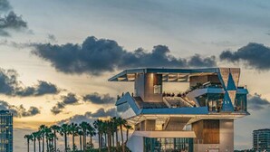 A modern waterfront hotel with a unique architectural design, featuring multiple levels and balconies, located near a pier with palm trees. - MODERN/Mins to Beach/walk to dwtn/Free parking (Tarpon Springs)