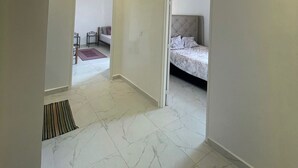 Un dormitorio moderno con una cama, una puerta que da a otra habitación e iluminación empotrada en el techo.