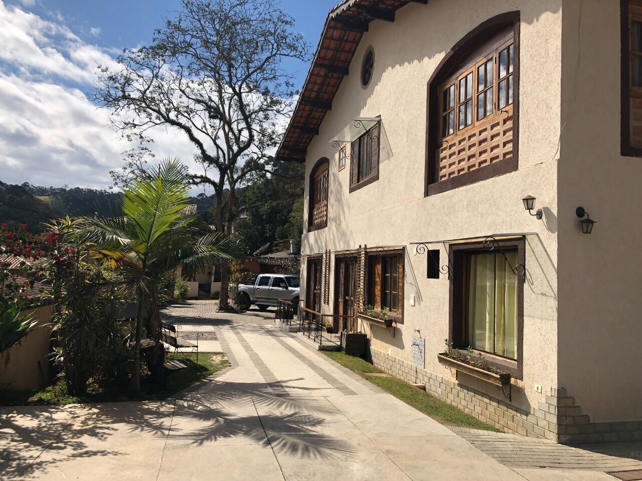 Un edificio con tejado de tejas, varias ventanas con contraventanas y un camino empedrado que lleva a la entrada.