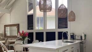 Eine moderne Küche mit einer großen Kochinsel, weißen Schränken und Blick durch hohe Fenster.