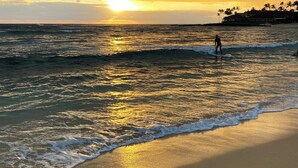 Ein Strand mit Wellen und einem Sonnenuntergang.