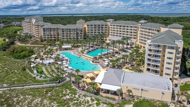 A resort with multiple buildings, a central pool, and surrounding palm trees. - Sea Dunes #1614 - Ocean front! (Nassau County)