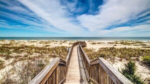 A wooden boardwalk leading to a beach with dunes and a clear sky. - Sea Dunes #1614 - Ocean front! (Nassau County)