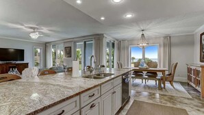 A spacious kitchen with a granite countertop, white cabinetry, and a large island. - Sea Dunes #1614 - Ocean front! (Nassau County)