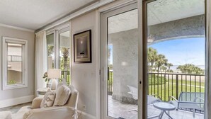A room with a sliding glass door leading to an outdoor patio with a table and chairs. - Sea Dunes #1614 - Ocean front! (Nassau County)