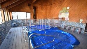 Una piscina interior con cubierta de madera, paredes de piedra y barandillas de metal.