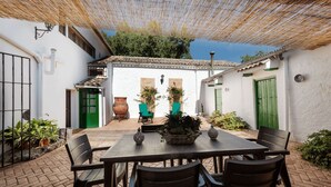 A courtyard with a table and chairs, surrounded by white walls and green doors. - Rural house with patio and garden (Alcalá la Real)