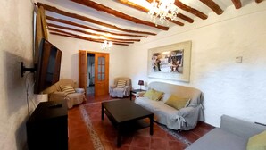 A cozy living room with a television, two sofas, a coffee table, and a chandelier. - Rural house with patio and garden (Alcalá la Real)
