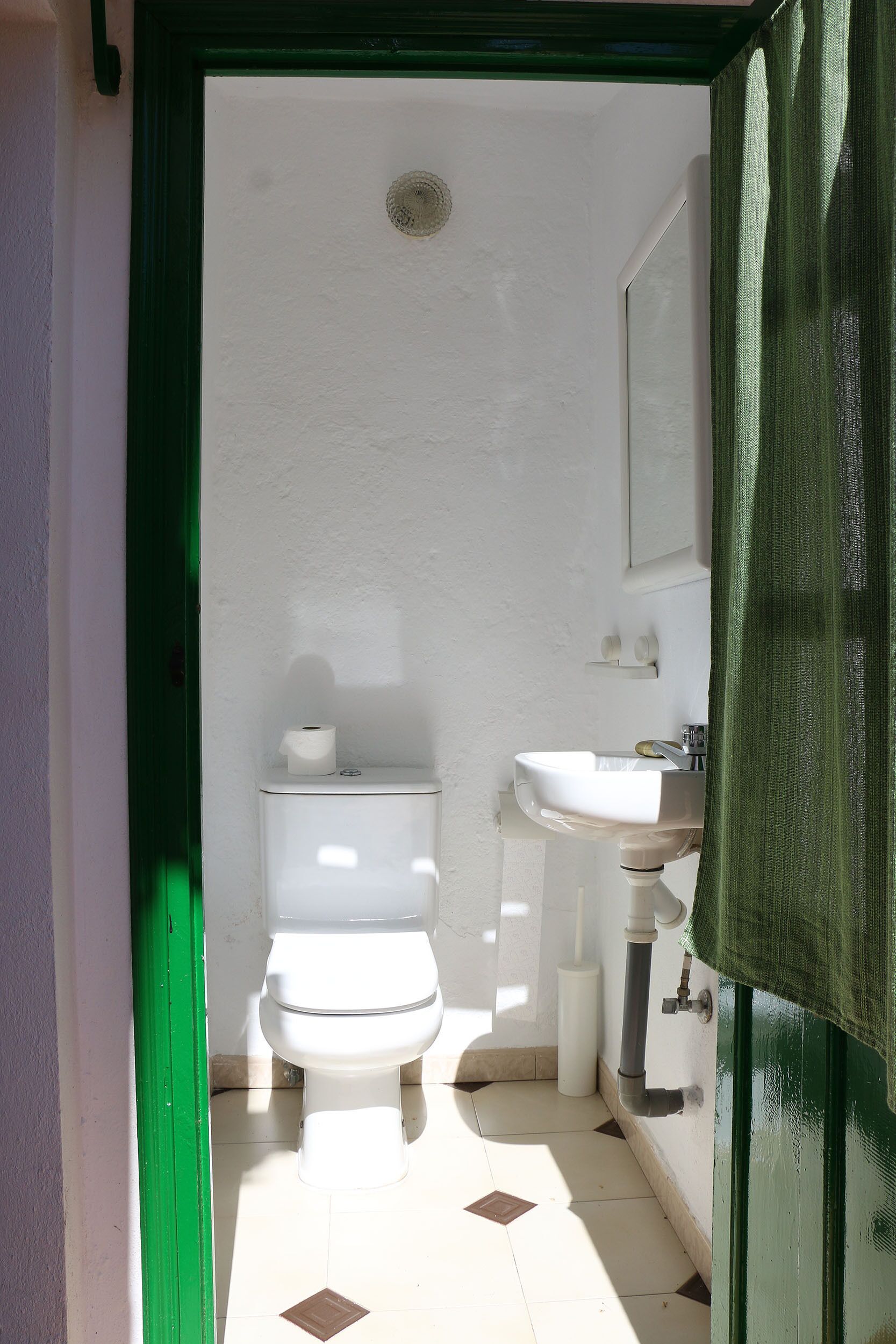 A small bathroom with a toilet, sink, and a mirror.