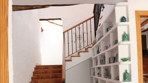 A staircase with a white railing leading to a landing with a white shelf unit displaying decorative items. - Rural house with patio and garden (Alcalá la Real)