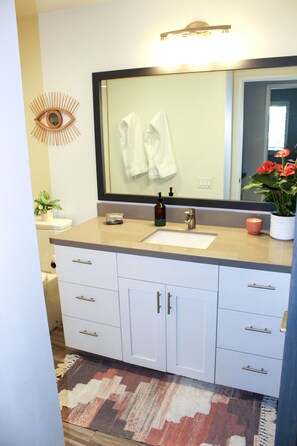 A bathroom with a sink, mirror, and cabinets. - Modern & Chic One Bedroom Condo, centrally located (Palm Springs)