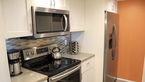 Una cocina moderna con electrodomésticos de acero inoxidable, incluyendo un microondas, horno y refrigerador.