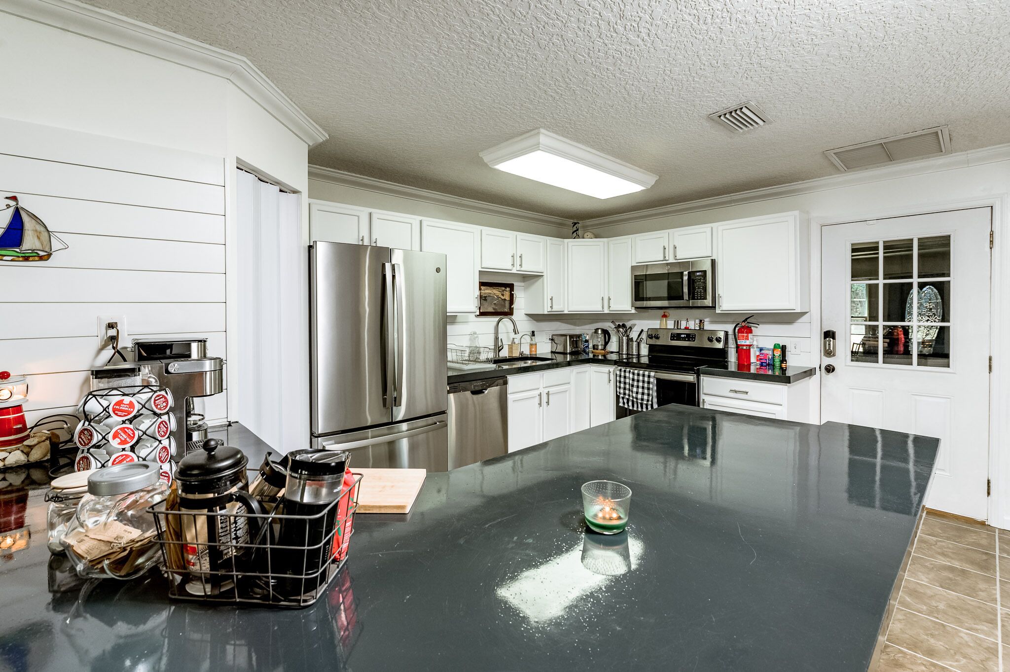 A modern kitchen with white cabinets, stainless steel appliances, and a black countertop.