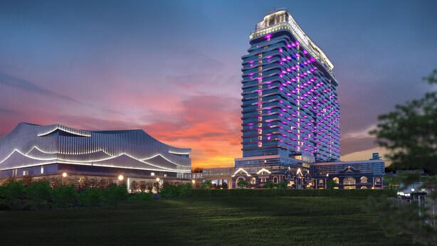 Un hotel modern amb una façana corba i única i un edifici alt amb il·luminació morada.