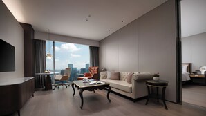 Habitació d'hotel moderna amb un finestra gran que ofereix vistes a la ciutat, un sofà, una taula de cafè i una zona de treball.