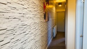 A hallway with a textured wall, a radiator, and a door at the end. - Townhouse @ 110 Etruria Vale Road Stoke (Stoke-on-Trent)
