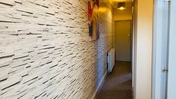A hallway with a textured wall, a radiator, and a door at the end.