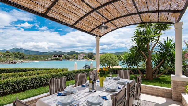 An outdoor dining area with a table set for six, overlooking a scenic coastal view. - Holiday Villa Lovište Paradise (Orebic)