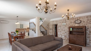 A living room with a sofa, coffee table, and a wooden cabinet. There is a staircase leading to an upper floor. - Holiday Villa Lovište Paradise (Orebic)