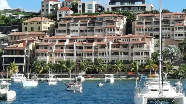 Un port de plaisance où sont amarrés de nombreux bateaux, avec en arrière-plan des immeubles à plusieurs étages dotés de balcons.