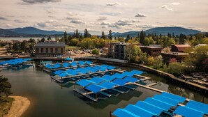 A marina with docked boats, a building with a large window, and a mountainous backdrop. - Upscale Lakeview Condo in Downtown Sandpoint (Sandpoint)