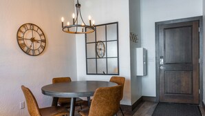 A dining area with a round table, four chairs, two wall clocks, and a door with a keypad lock. - Upscale Lakeview Condo in Downtown Sandpoint (Sandpoint)