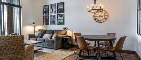 En moderne stue med sofa, spisebord, stole og en lysekrone.