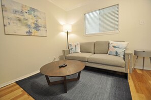 A living room with a beige sofa, a round coffee table, and a floor lamp.