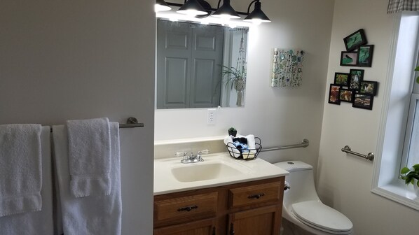 A bathroom with a white sink, wooden cabinets, a glass shower enclosure, and a toilet.