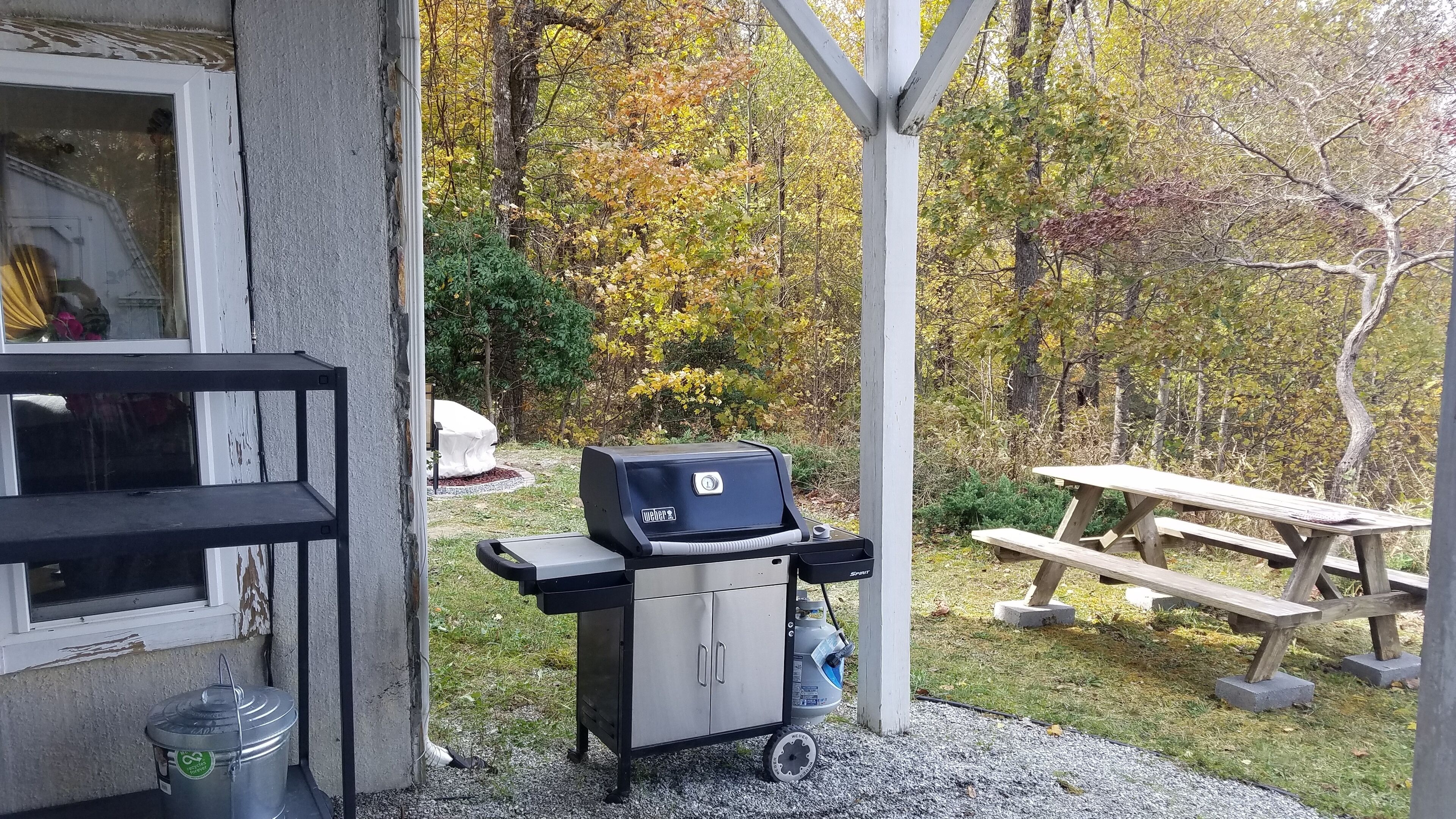 Eine Terrassenfläche mit Grill, Picknicktisch und Außenschränken.
