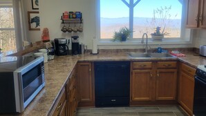 A kitchen with granite countertops, wooden cabinets, a dishwasher, a coffee maker, and a window with a view of mountains. - Mountaintop suite, mountain views, one level, King bed, pet friendly, accessible (Rosman)