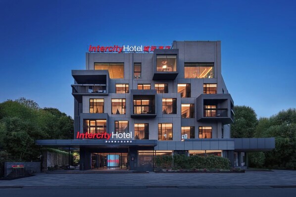 Un hôtel moderne, avec plusieurs étages et des balcons, qui se distingue par son entrée imposante et une enseigne bien visible.