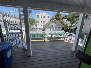 A covered deck with picnic tables and a basketball hoop, overlooking a residential area with houses and a garage. - 1913 Classic Victorian Home with manny outdoor spaces. (Wildwood)