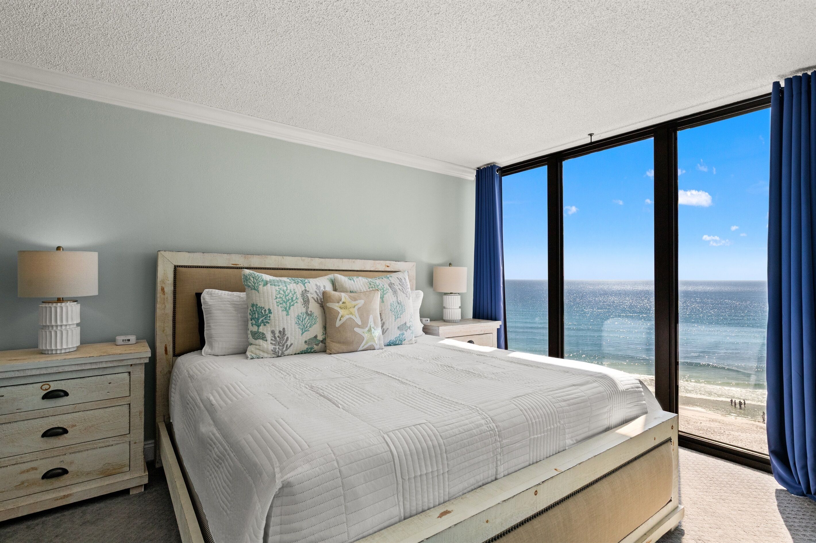 Una camera da letto con un letto grande, un comodino con una lampada e vista sull'oceano.