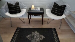 Dos sillas con cojines de estampado negro, una mesita con una vela y una alfombra de diseño blanco y negro.