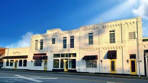 A white building with multiple storefronts, including a barber shop and a restaurant. - Vintage Q ensuite room, historic railroad hotel (Cowan)