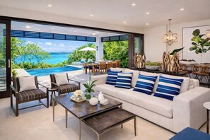 A modern living room with a large window overlooking a pool and ocean view. -  EXCLUSIVE DESIGNER WATERFRONT 4 BDR VILLA CHEF POOL BEACH ACCESS (Montego Bay)