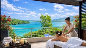 Un entorno de spa con una camilla de masaje, un masajista y una vista panorámica al océano.