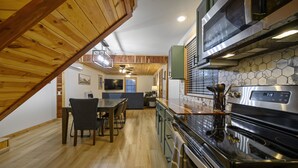 A modern kitchen with wooden beams, a dining area, and a microwave.
