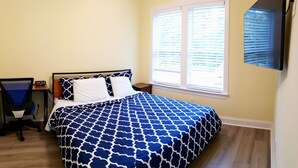 A bedroom with a bed, a chair, a nightstand, and a window with blinds. - Mulberry Cottage on 16 Acres, King Size Bed, No Pet Fee (Grovetown)