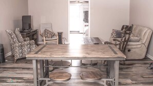 A compact living space with a dining table, a sofa, a recliner, a TV, and a ceiling fan. - 2-bedroom Barn 1-bathroom Apartment Sleeps 7  (Parkton)