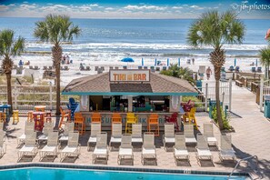Eine Strandbar namens 'TIKI BAR' mit einer Sitzgelegenheit am Pool und Blick auf den Ozean.