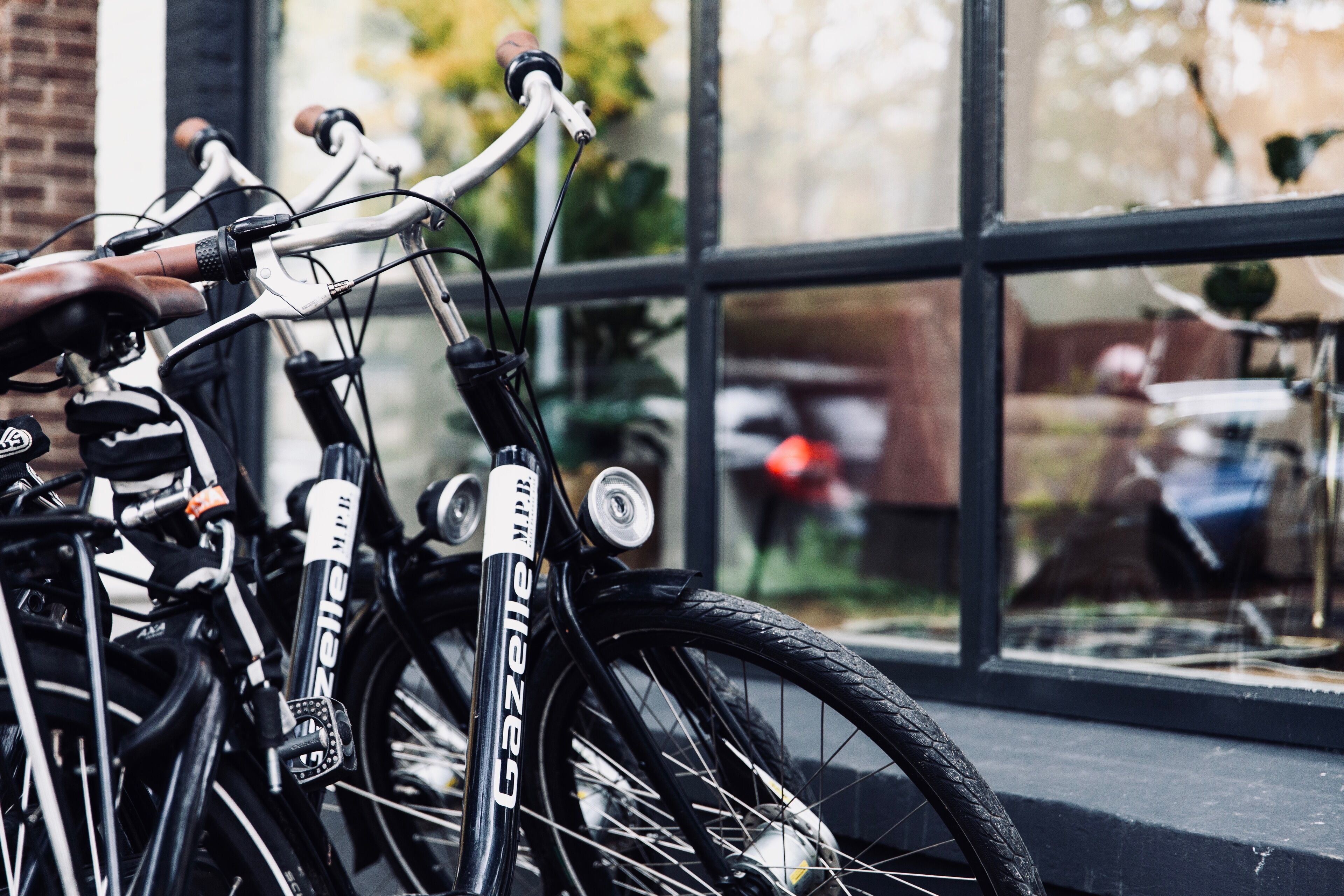 Een fiets met het merk 'Gazelle' geparkeerd voor een gebouw met grote ramen.