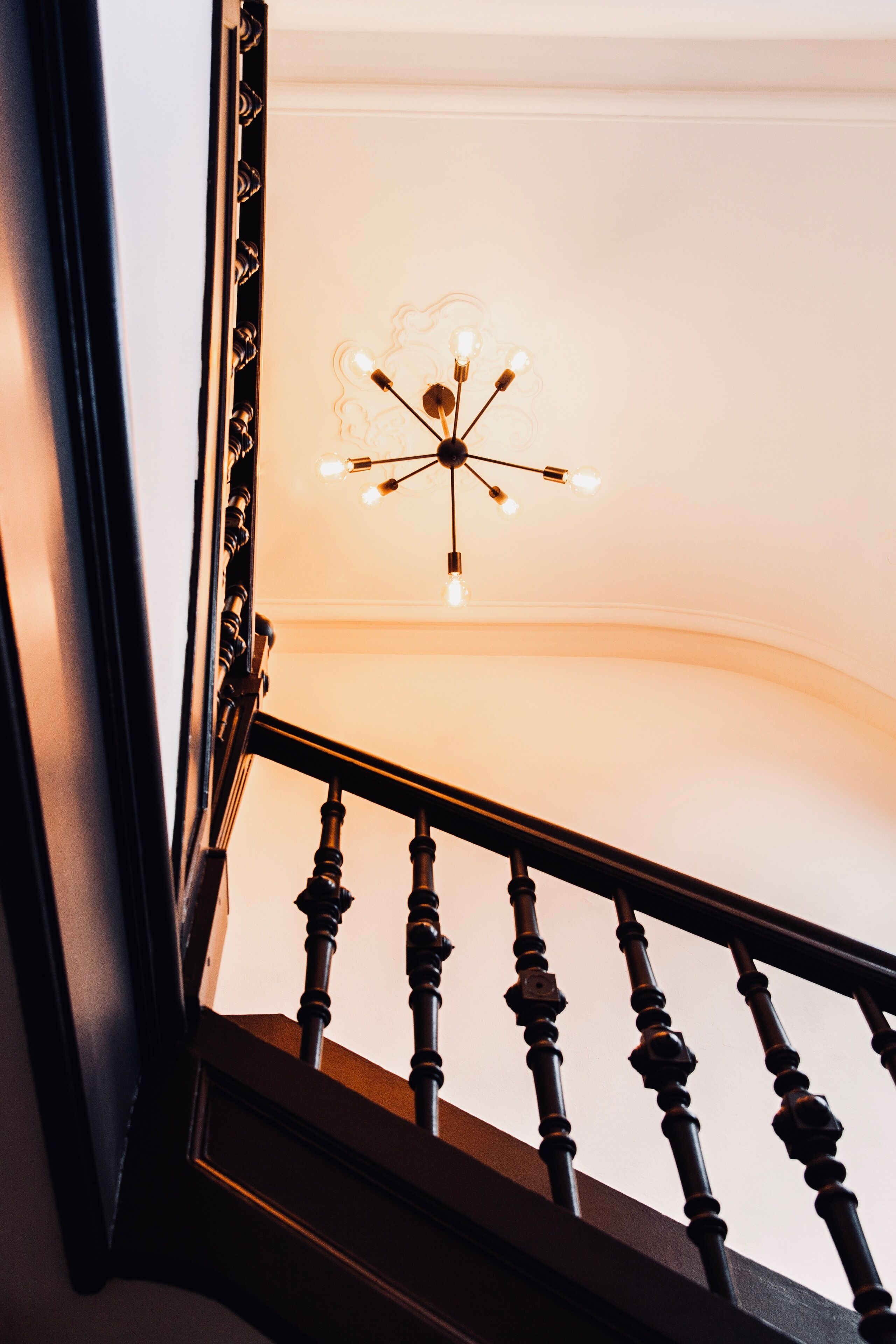 A staircase with a wooden railing and a ceiling light fixture.