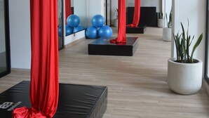 A spacious indoor area with a modern design, featuring red curtains, exercise balls, and a black platform.