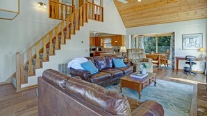 A spacious living area with a wooden staircase, leather sofas, a dining area, and a view of the outdoors. - Luxury Mountaintop Views with Hot Tub - 1 min to town (Hiawassee)