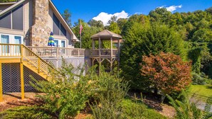 A two-story house with a stone facade, a wooden deck with a railing, and a gazebo. - Luxury Mountaintop Views with Hot Tub - 1 min to town (Hiawassee)