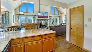 A spacious kitchen with wooden cabinets, a granite countertop, and large windows offering views of the outdoors. - Luxury Mountaintop Views with Hot Tub - 1 min to town (Hiawassee)