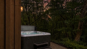 A hot tub in a wooded area with steps leading up to it.
